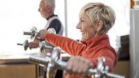 Smiling Senior couple in gym working out using dumbbell