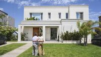 Hispanic seniors admiring modern family home from front yard