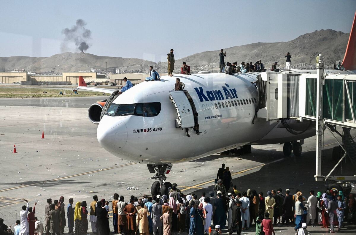 Afghan people climb atop a plane as they wait at the Kabul airport in Kabul on August 16, 2021, after a stunningly swift end to Afghanistan's 20-year war, as thousands of people mobbed the city's airport trying to flee the group's feared hardline brand of Islamist rule. Afghan people climb atop a plane as they wait at the Kabul airport in Kabul on August 16, 2021, after a stunningly swift end to Afghanistan's 20-year war, as thousands of people mobbed the city's airport trying to flee the group's feared hardline brand of Islamist rule.