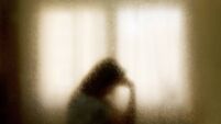 Blurred silhouette of a woman in emotional distress .