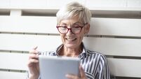 Old good looking woman sitting and use tablet to comunicate with her long distance family