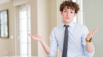 Young business man wearing a tie clueless and confused expression with arms and hands raised. Doubt concept.