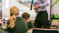 Primary school girls are taught during a lesson by a male teacher