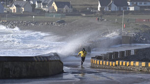 <p> A man running from huge waves created by a storm in Garretstown, Co Cork, in 2025. File picture: Dan Linehan</p>