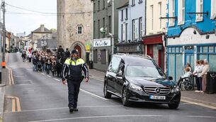 <p>A garda officer ahead of the cortege for Jack Kennedy as it made its way through Athy, Co Kildare, ahead of his funeral at St Michael's Parish Church in the town. Photo: Evan Treacy/PA Wire</p>
