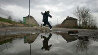 a child leaps over a puddle on a poverty stricken estate in Maryhill Glasgow