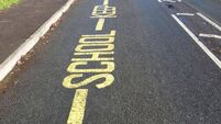 Yellow warning sign, School Keep Clear, painted tarmac road, no-parking