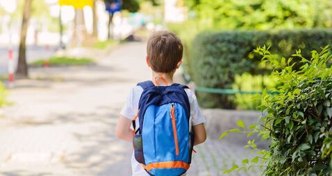 Little 7 years schoolboy going to school.