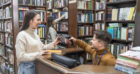 Young woman renting a book in a school library