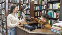 Young woman renting a book in a school library