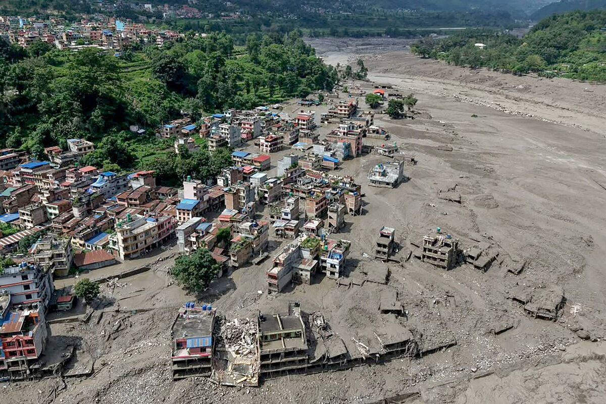 Houses lie partially submerged in muddy water along a riverside after flash floods at Trishuli Bazar in Nepal's Nuwakot district on August 26, 2026. (Photo by Prabin RANABHAT / AFP via Getty Images)