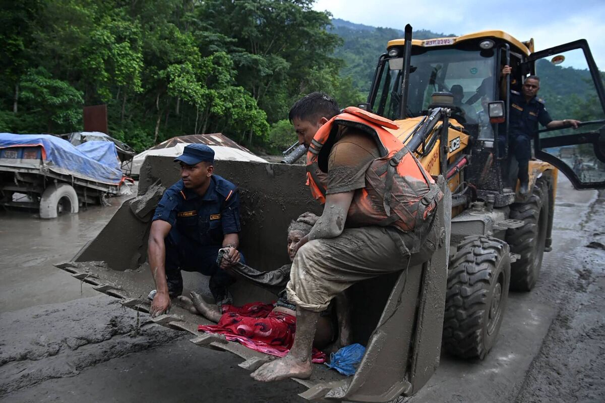 Rescue personnel use an excavator to carry a person affected by flash floods at Devghat in Nepal's Nuwakot district on August 26, 2026.(Photo by Prakash MATHEMA / AFP via Getty Images)