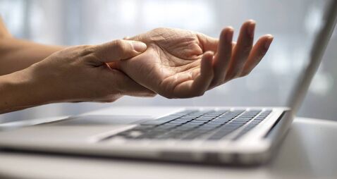 Woman massaging painful wrist at work repetitive strain injury
