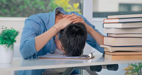 student at desk with stressed or overwhelmed books