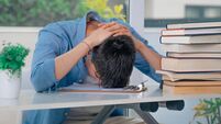 student at desk with stressed or overwhelmed books