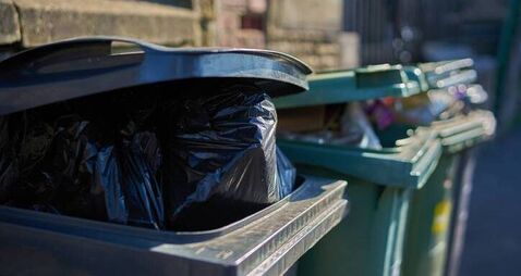 Overfull garbage cans wheelie bins close up