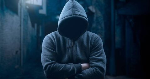 dangerous hooded man at night in dark alley. bandit, criminal with an unrecognizable face in threatening pose at night on dark s