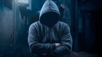 dangerous hooded man at night in dark alley. bandit, criminal with an unrecognizable face in threatening pose at night on dark s
