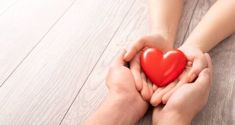 The adult and the child holding red heart.