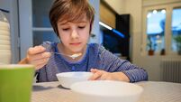 Preadolescent boy having cereal with milk for breakfast at the dining table at home