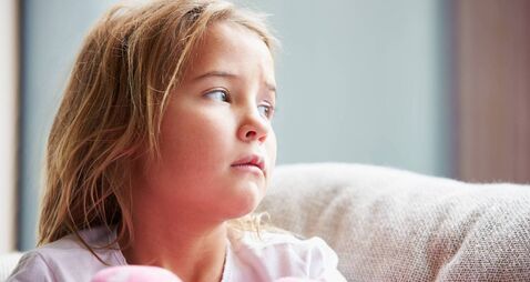 Physically Abused Child At Home Sitting On Sofa