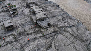 A drone view shows rescue workers inspect the area and damaged structures following recent flash flooding (Rajesh Kumar Singh/AP)