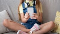 Girl using her smart phone sitting on couch