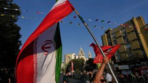 A man holds an Iranian flag during a street celebration marking the Prophet Muhammad’s birthday, in Tehran (Vahid Salemi/AP)