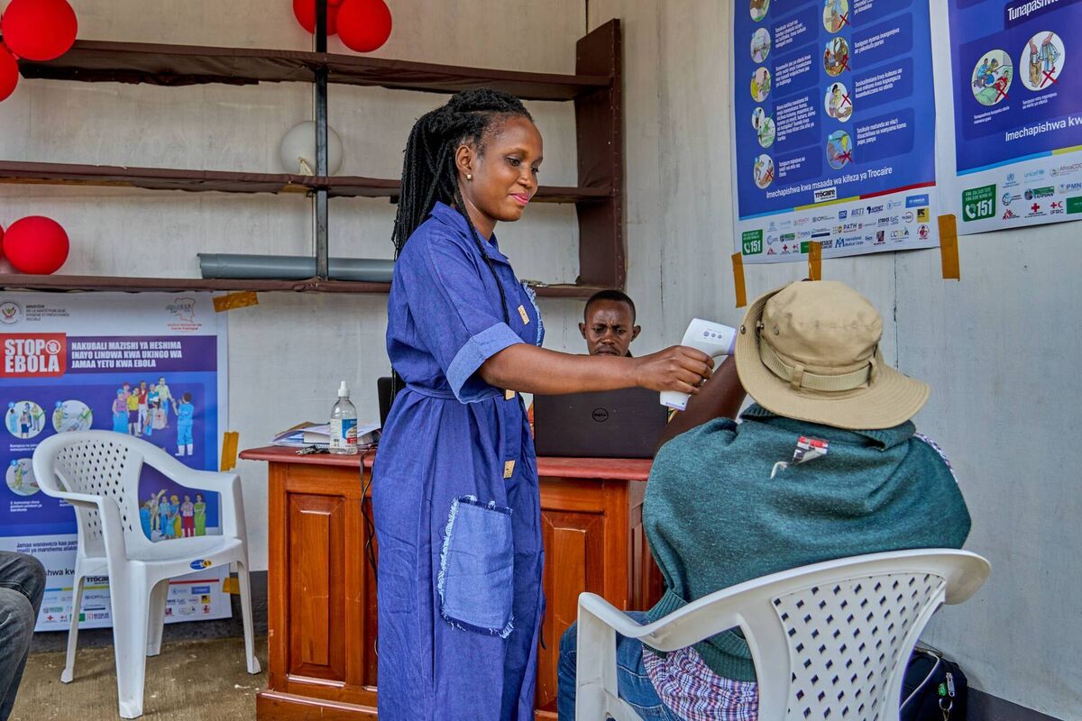Rose Drajima Kpawi, a community mobiliser at the Caritas Bunia ebola Information Kiosk, uses a non-contact infrared thermometer to screen a visitor before providing information on Ebola. Rose Drajima Kpawi, a community mobiliser at the Caritas Bunia ebola Information Kiosk, uses a non-contact infrared thermometer to screen a visitor before providing information on Ebola.