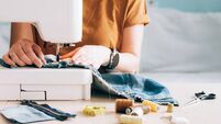 A woman tailor works at sewing machine sews reuses fabric from old denim clothes