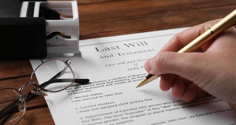 Woman signing Last Will and Testament at wooden table, closeup