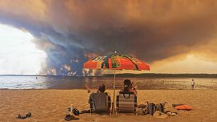 <p>Beachgoers at Moutchic in Lacanau, southwestern France in July as clouds of smoke rise into the sky from a wildfire. El Niño could make next year the hottest on record. Picture: Maximilien Lamy/AFP via Getty Images</p>