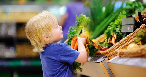 iStock-612261820.jpg Cute toddler boy in supermarket choosing fresh organic carrots