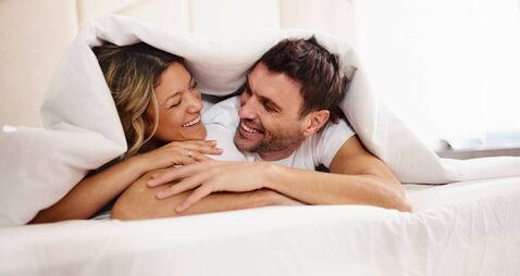 Affectionate couple talking in a bed during morning time.