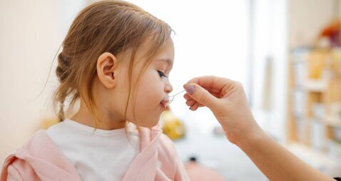 Mother giving medicine to little girl
