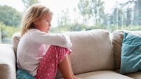 Unhappy Young Girl Sitting On Sofa At Home