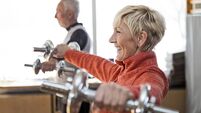 Smiling Senior couple in gym working out using dumbbell