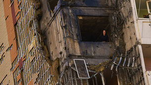 A woman peers from a window of a damaged residential building following a Russian drone attack in Kyiv (Francisco Seco/AP)