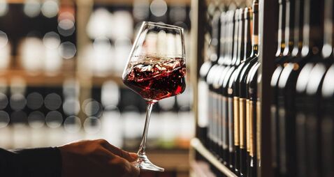 iStock-2166045624.jpg Close-Up View of Person Swirling Red Wine in Cellar Atmosphere