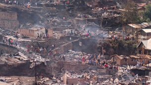 People walk amid the charred remains of homes near a primary school and a secondary school (Janvier Barhahiga/AP) People walk amid the charred remains of homes near a primary school and a secondary school (Janvier Barhahiga/AP)