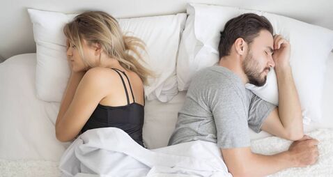 Young couple sleeping back to back in their bed