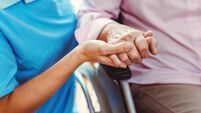Nurse consoling a senior woman in the nursing home holding her hand in the nursing home
