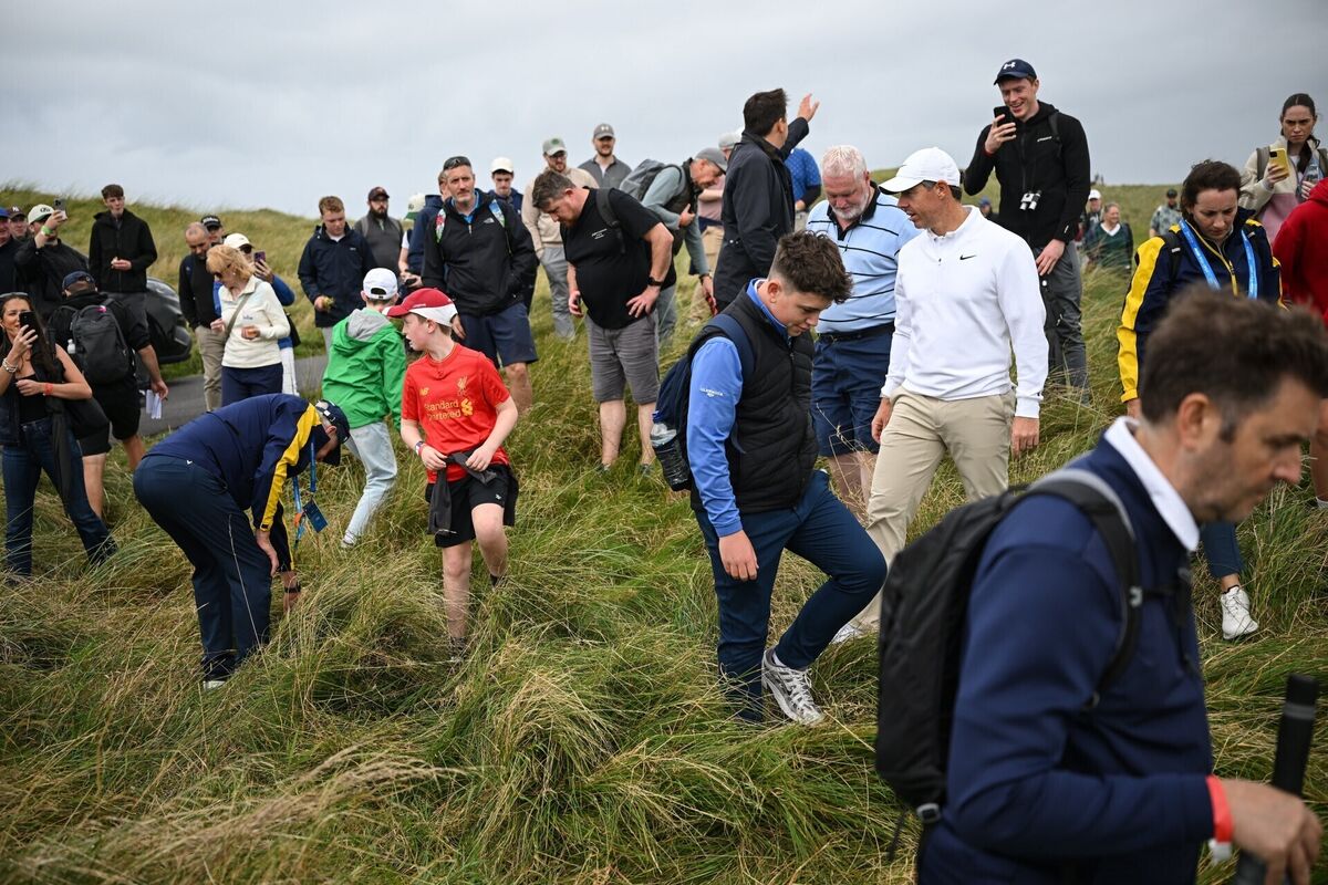 Rory McIlroy with the help of spectators, looks for the ball of Adrian Meronk. Pic: Ramsey Cardy/Sportsfile. Rory McIlroy with the help of spectators, looks for the ball of Adrian Meronk. Pic: Ramsey Cardy/Sportsfile.