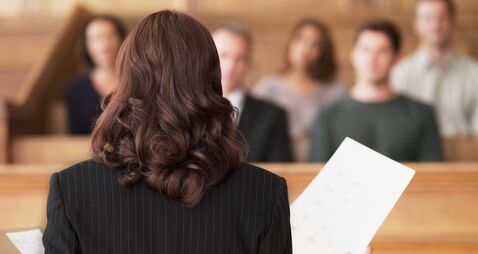 Lawyer holding document and speaking to jury in courtroom