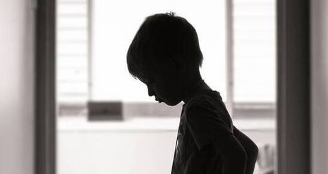 Sad boy standing alone in the hallway
