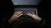 2G9N95T A simple, very dark night time image of hands on an illuminated keyboard typing. Shady person wearing a hood at a computer or la