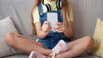 Girl using her smart phone sitting on couch