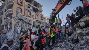 Palestinian civil defence crews carry a body from the rubble of the collapsed building (Jehad Alshrafi/AP)