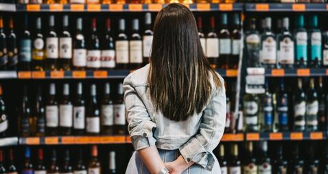 Woman customer looking at a rack of wine in supermarket