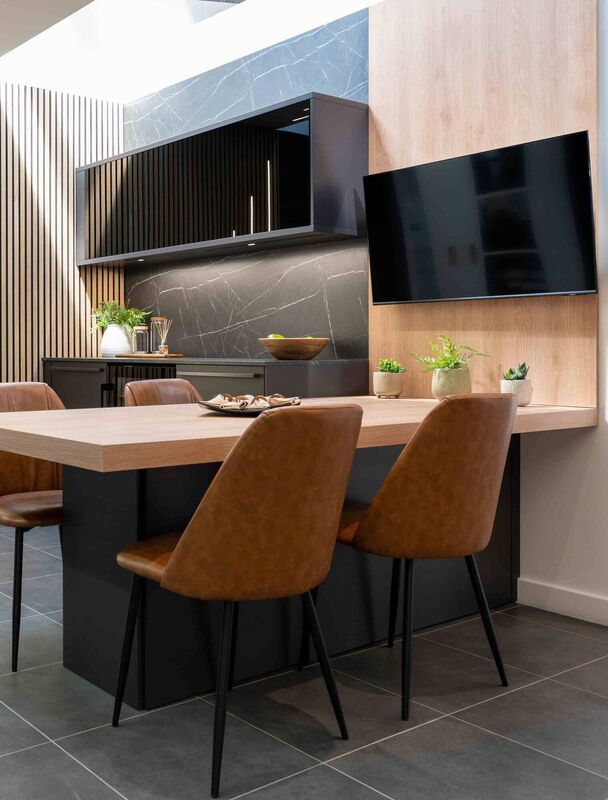 A wooden peninsula breakfast bar with chair seating in mottled leather and matt black cupboards with pull-down shutters creating a comfy breakfast area. Picture: The Used Kitchen Company/PA A wooden peninsula breakfast bar with chair seating in mottled leather and matt black cupboards with pull-down shutters creating a comfy breakfast area. Picture: The Used Kitchen Company/PA